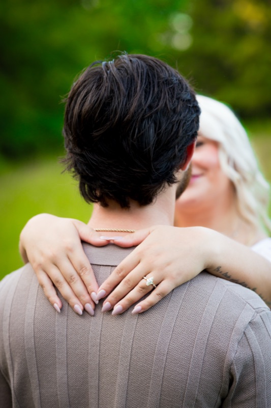 Her arms around his neck, ring showing