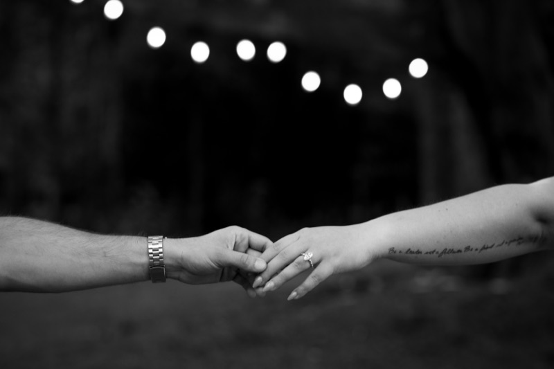 Hands reaching under string lights