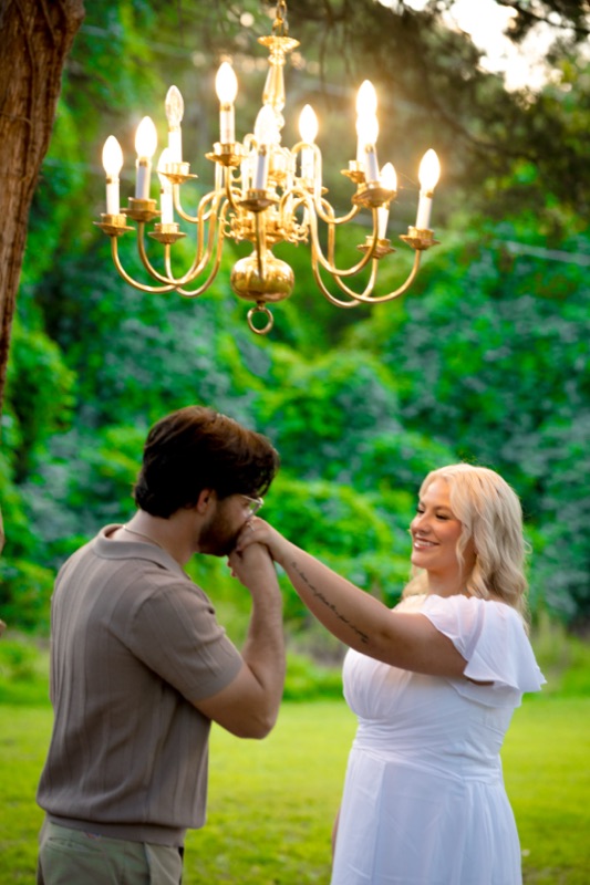 A kiss on the hand under a chandelier in the trees